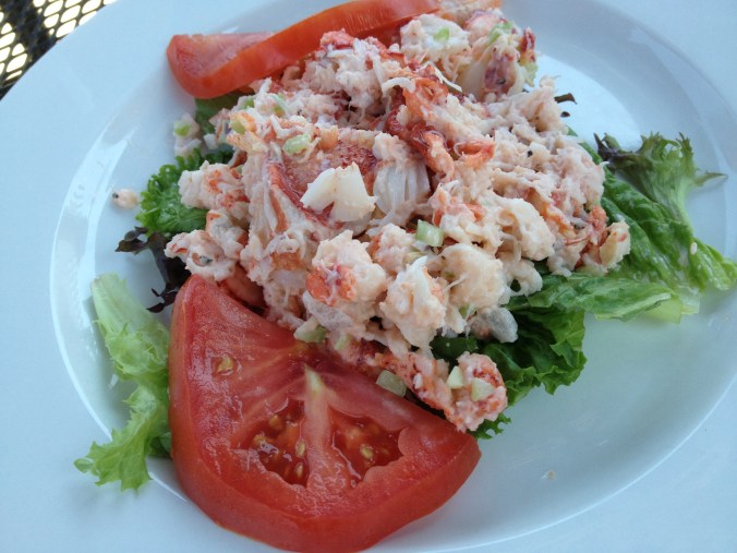 Chunks of lobster salad over lettuce with slices of tomato